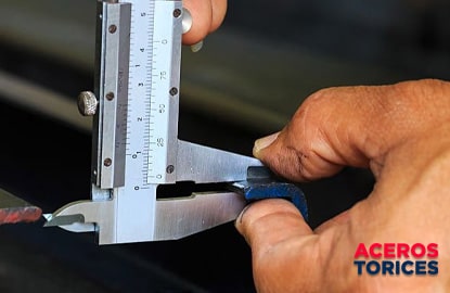 trabajador usando un calibrador vernier Trabajador usando un calibrador vernier para medir una pieza de acero