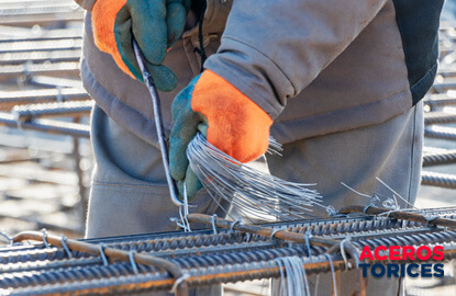hombre amarrando alambres galvanizados a estribos Hombre sujetando alambres galvanizados a estribos en construcción