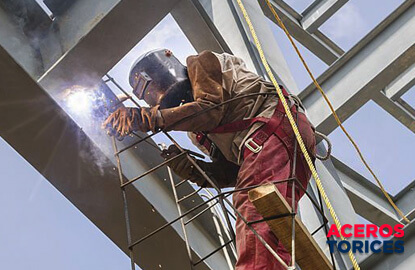 Trabajador de la construcción uniendo vigas de acero con soldadura