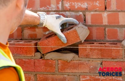 trabajador verificando la hilada de un muro Trabajador colocando ladrillos con la hilada correctamente alineada