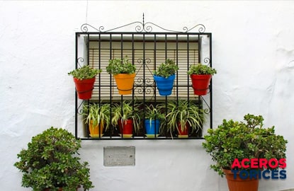 Ventana de herrería con cuatro macetas instaladas en sus anillas de acero