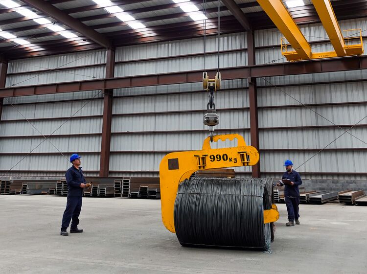Trabajadores moviendo un rollo de acero recocido con una grúa dentro de una bodega